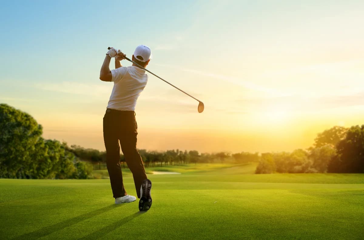 Golfer at the top of a tee shot in low evening light